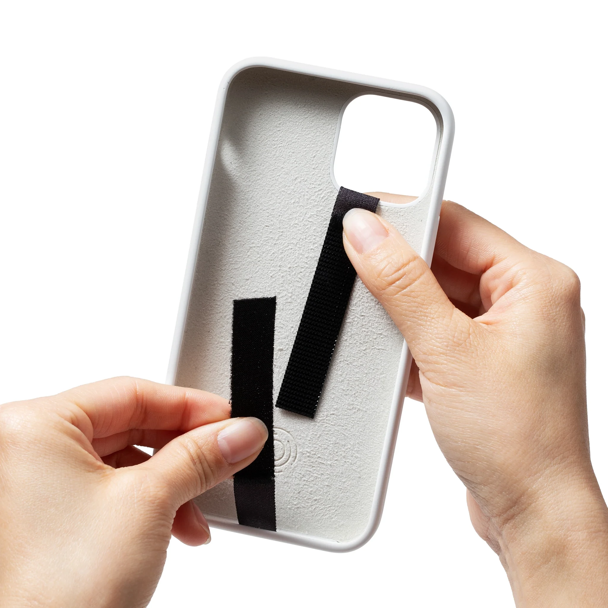 Two hands fitting a black strap through the back of a white phone case